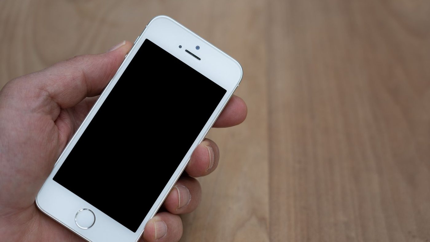 Phone held in one hand with a blank screen, used to test a review link