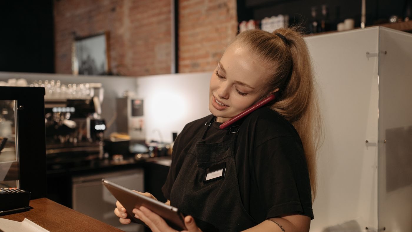 Staff member working at a cafe counter with a tablet