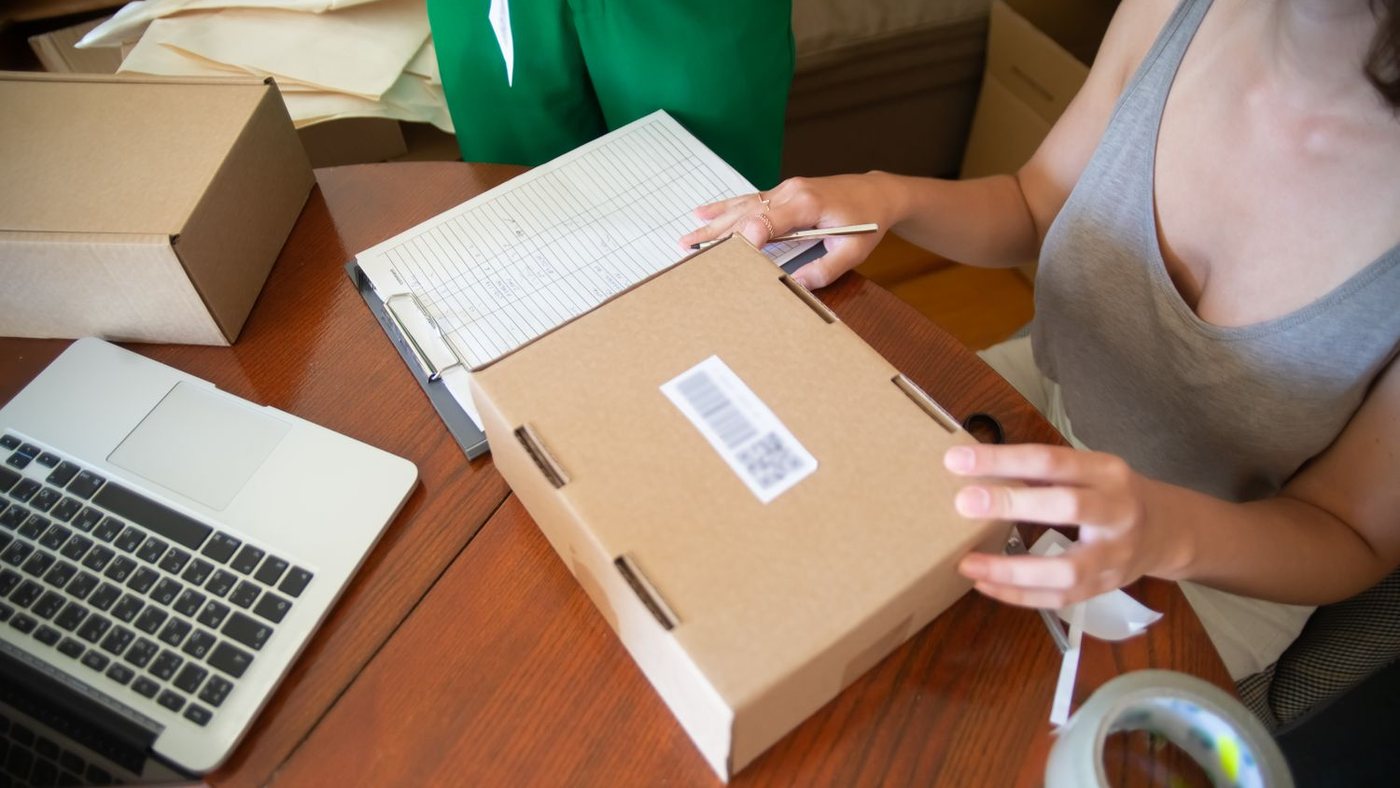 Store owner packing an order next to a laptop